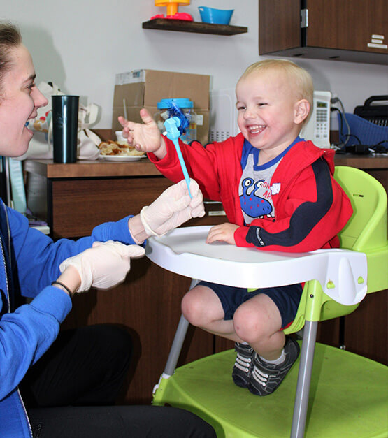 Child in assisted seating doing therapy with a smile on his face